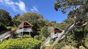 Dos cabañas de madera con balcones, rodeadas de exuberante follaje y árboles.