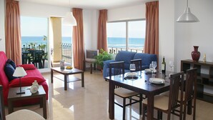 A spacious living area with a balcony overlooking the sea, furnished with a sofa, dining table, and chairs. - Apartamentos Euromar Playa (Torrox)