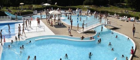 Una piscina al aire libre, sombrillas, sillones reclinables de piscina