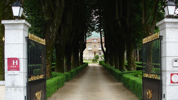 Une entrée fermée par un portail, avec un chemin menant à un bâtiment.