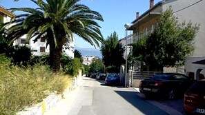 Una calle residencial con coches aparcados, una palmera y edificios.