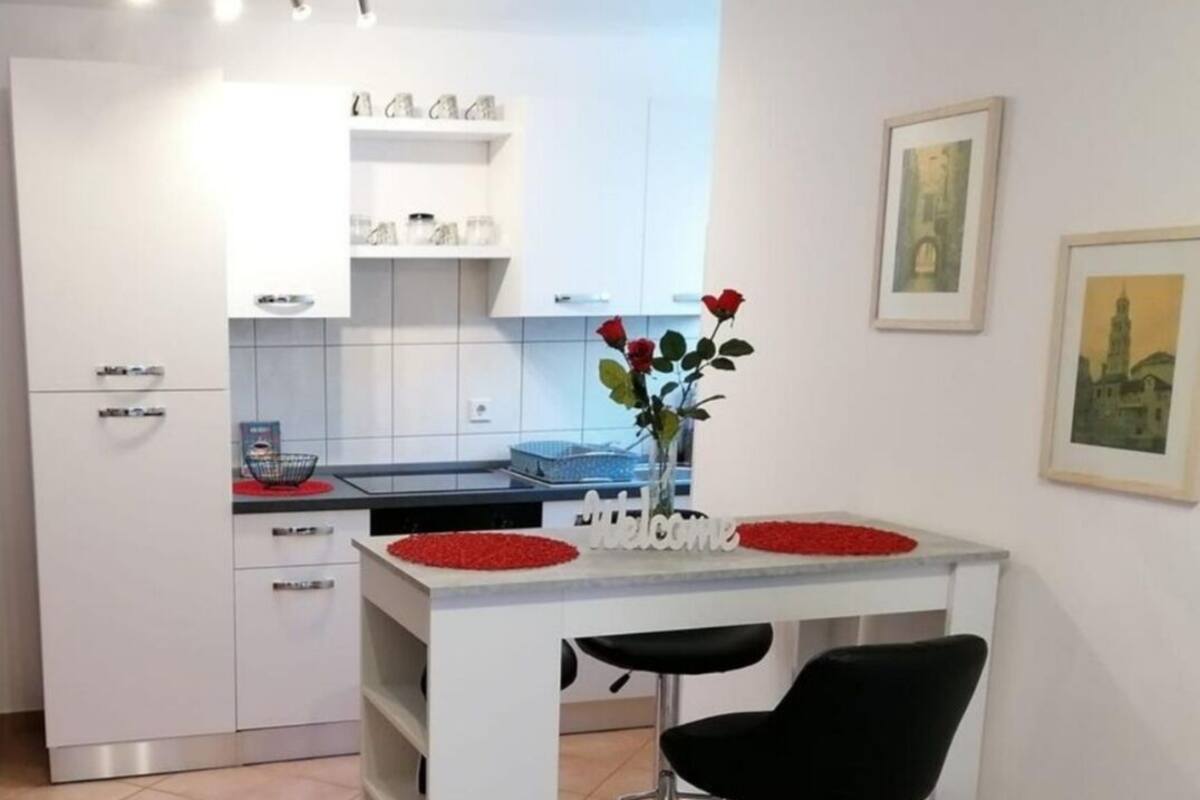 A modern kitchen with white cabinets, a black countertop, and a bar area with red accents.
