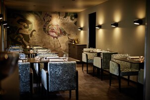 A restaurant interior with tables set for dining, chairs, and wall-mounted lighting.