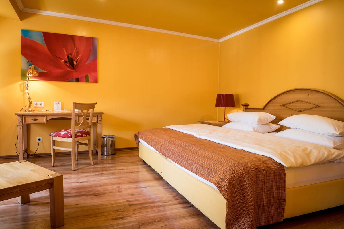 A bedroom with a bed, a desk, a chair, and a lamp.