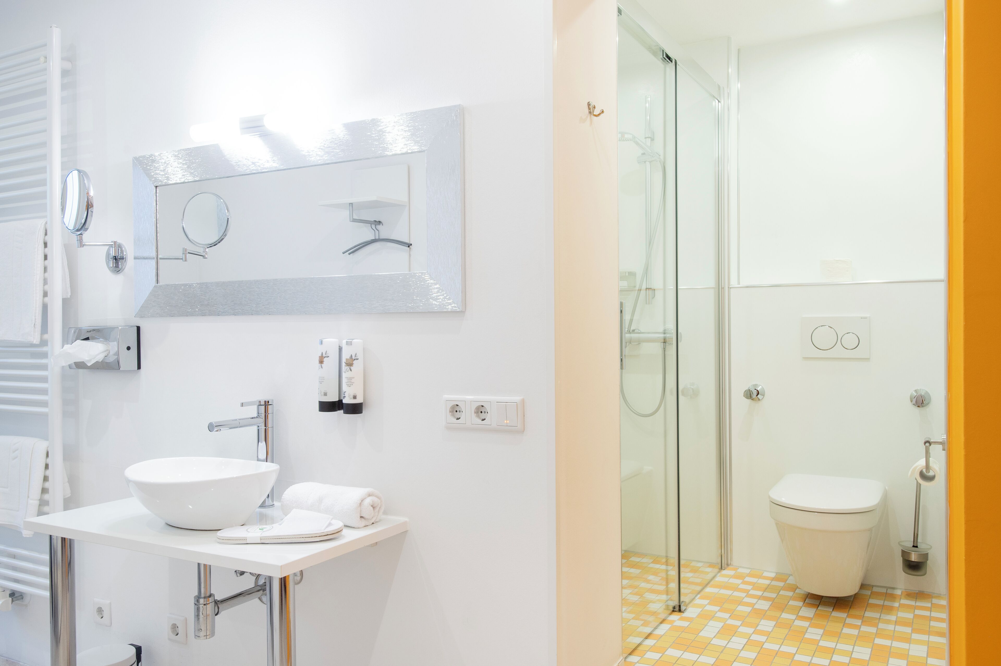 A modern bathroom with a white sink, mirror, and toilet.