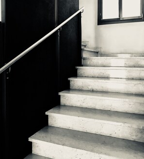Un escalier avec une rampe, menant à un palier doté d’une fenêtre.