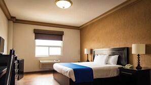 Una habitación de hotel con cama, lámparas de noche, un escritorio y una ventana con persianas.