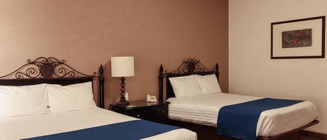 Two single beds with wooden frames and white bedding, a bedside table with a lamp, and a framed picture on the wall.