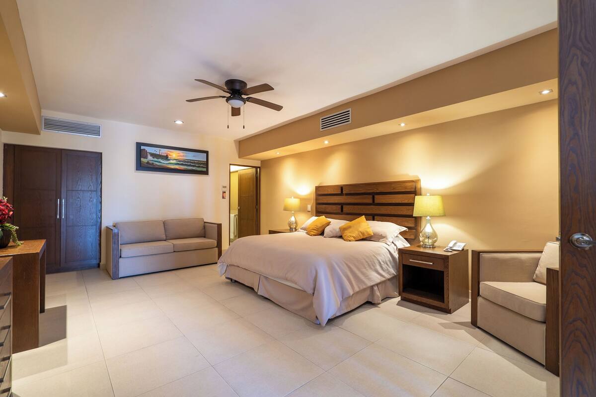Une chambre d’hôtel équipée d’un lit, d’un canapé, d’un bureau et d’un ventilateur de plafond.