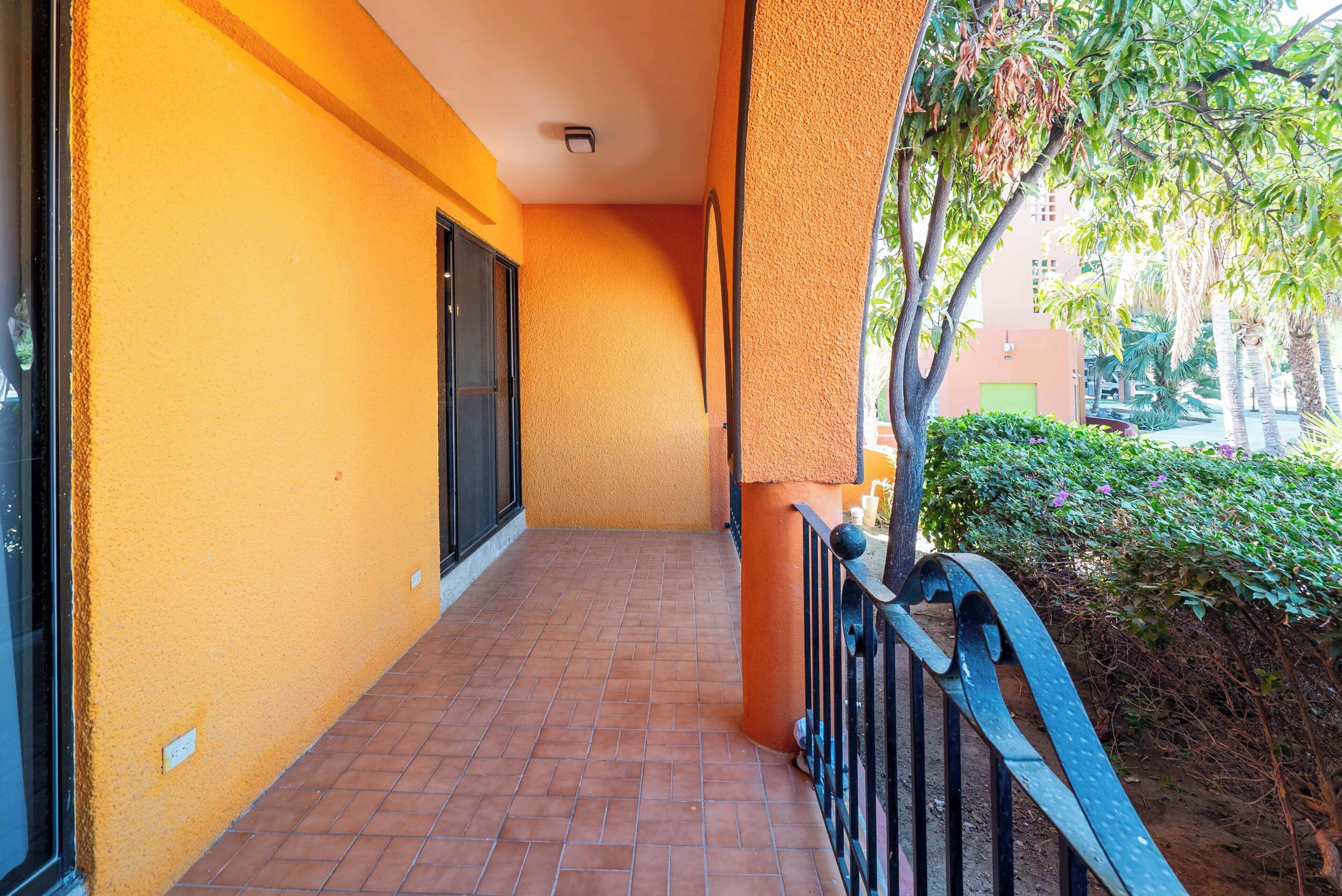 A corridor with orange walls, a tiled floor, and a metal railing.