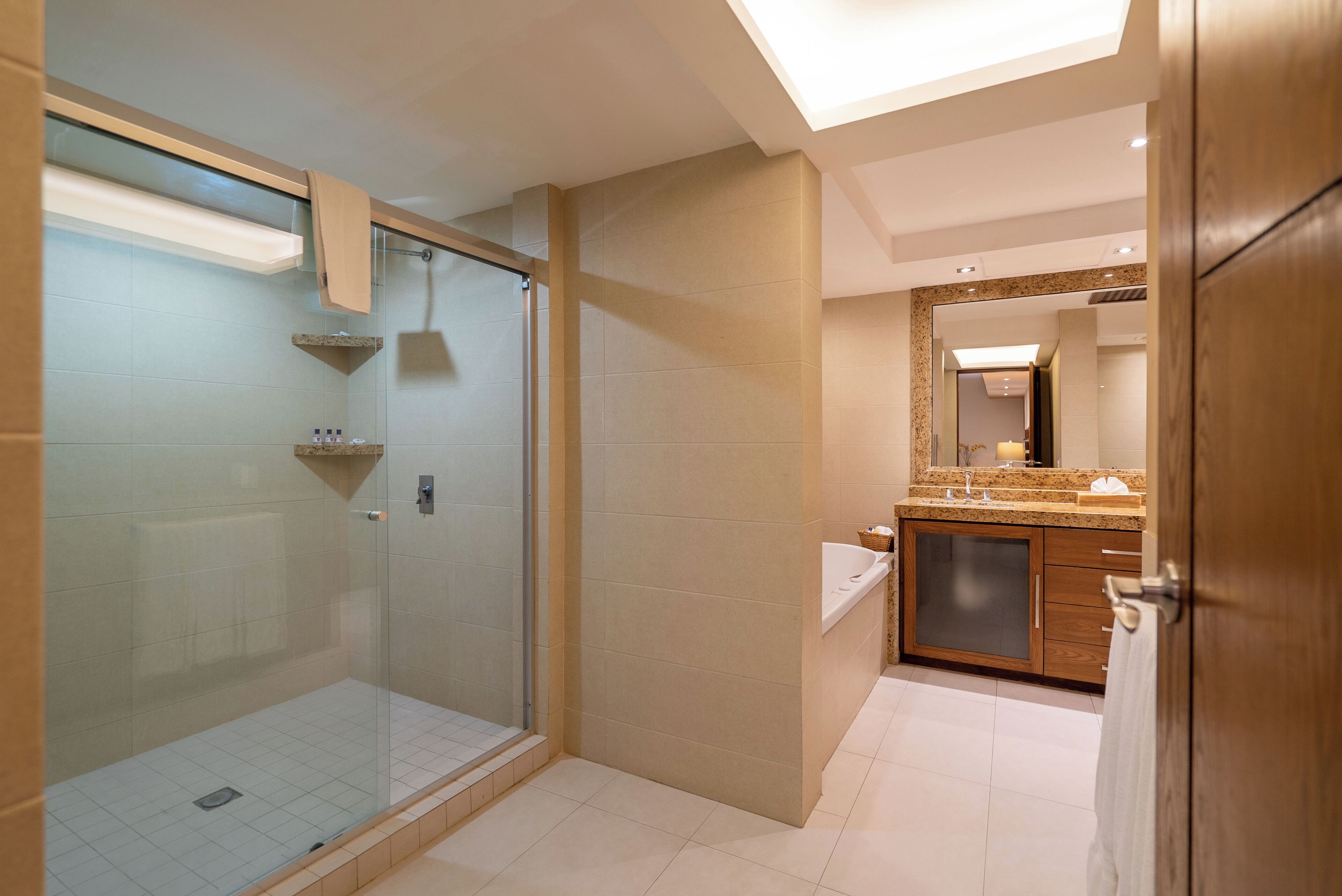 A modern bathroom with a glass shower enclosure, a vanity with a sink, and a large mirror.