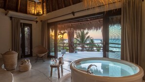 A luxurious room with a large bathtub, a ceiling fan, and a view of the ocean. - Hotel Villas Flamingos (Isla Holbox)