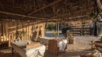 Experience a serene retreat with two massage tables set amidst a natural ambiance, surrounded by potted plants and soothing decor.