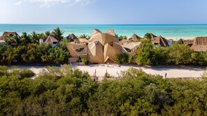 A beach resort with thatched-roof huts, a sandy beach, and a clear view of the ocean. - Hotel Villas Flamingos (Isla Holbox)