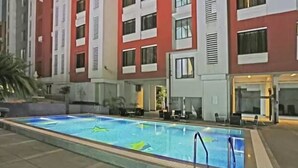 A swimming pool with a clear blue water surface, surrounded by a building with red and white exterior walls and multiple windows. - Keys Select by Lemon Tree Hotels, Nestor, Mumbai (Mumbai)