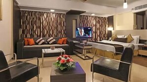 A modern hotel room with a sofa, a bed, a TV, and a coffee table with flowers. - Keys Select by Lemon Tree Hotels, Nestor, Mumbai (Mumbai)