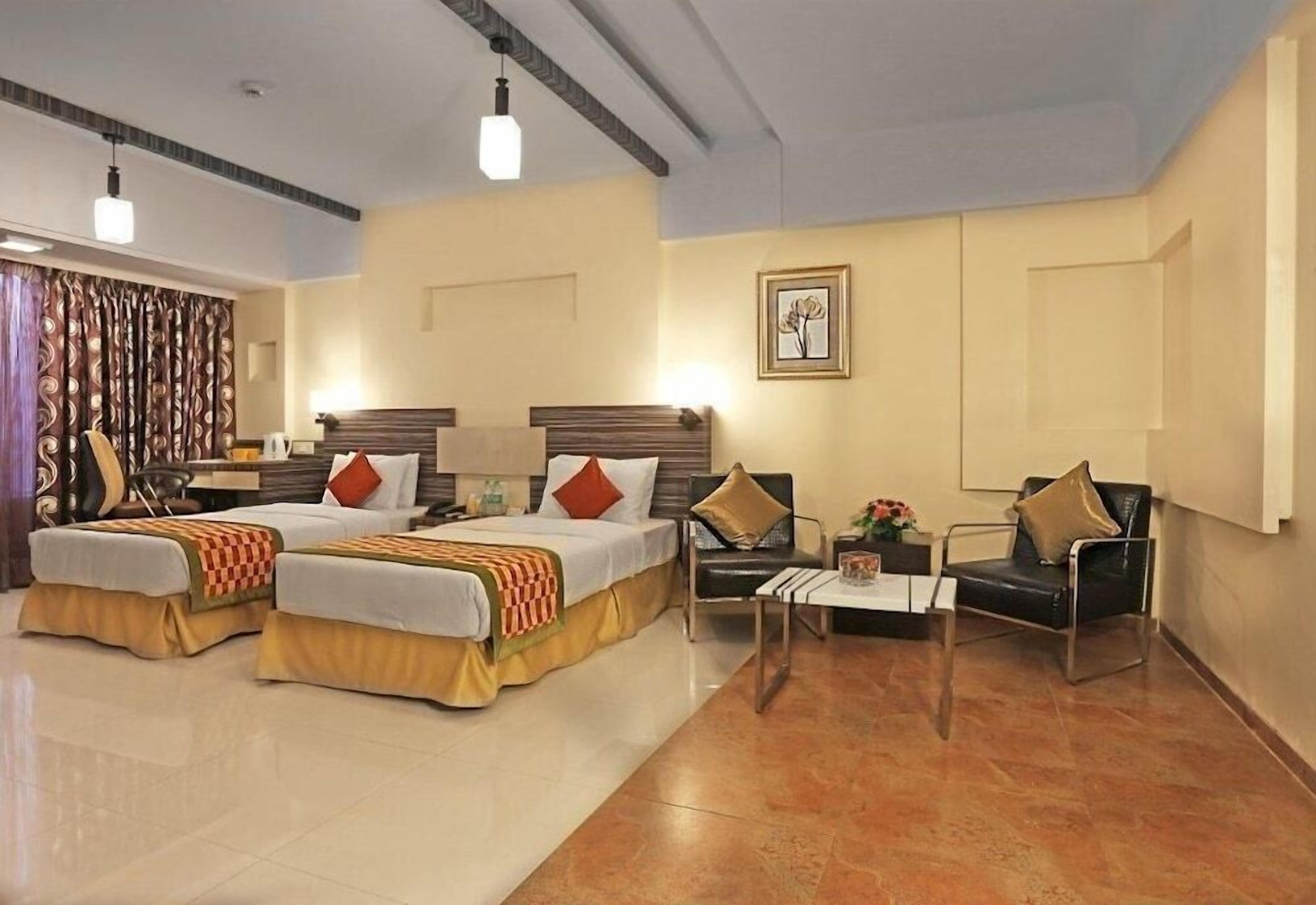 A hotel room with two beds, a sofa, a coffee table, and a chair.