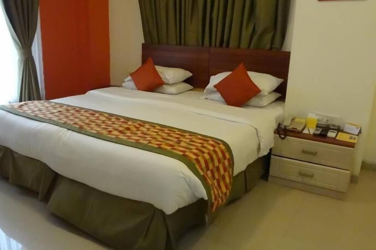 Una habitación de hotel con una cama, una mesita de noche y un aparador.
