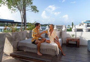 A couple sitting on a sofa with a view of boats and buildings in the background. - Be Playa Hotel Boutique & Rooftop Bar - Adults Only (Playa del Carmen)