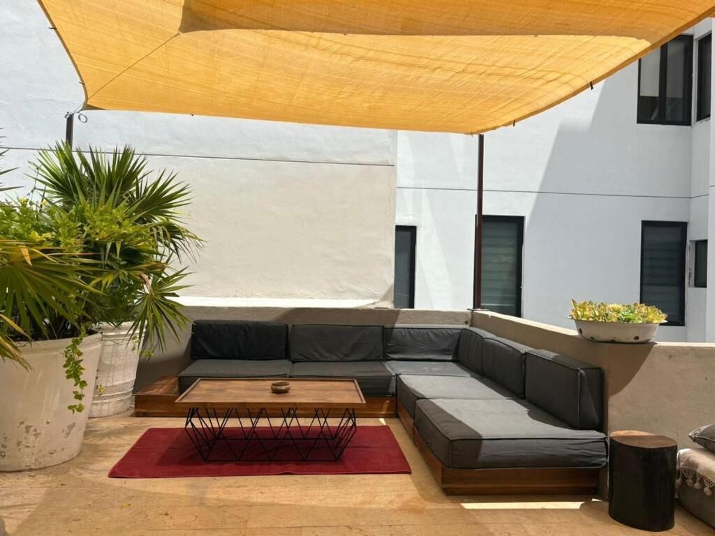 Un área de estar moderna al aire libre con un sofá modular, una mesa de centro de madera y una alfombra roja.