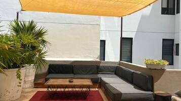 Un área de estar moderna al aire libre con un sofá modular, una mesa de centro de madera y una alfombra roja.