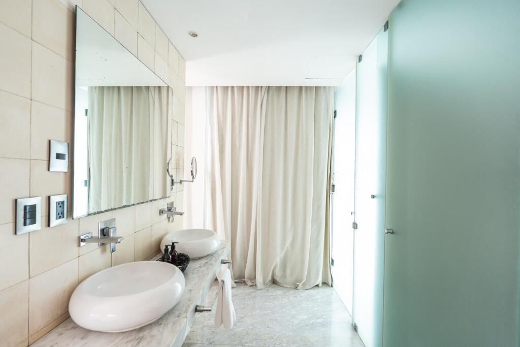 A modern bathroom with two sinks, a large mirror, and a shower curtain.