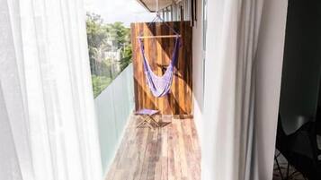 En balkon med hængekøje, trægulv og et hvidt badekar.