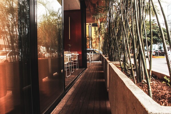 An outdoor seating area with tables and chairs, surrounded by tall bamboo plants.