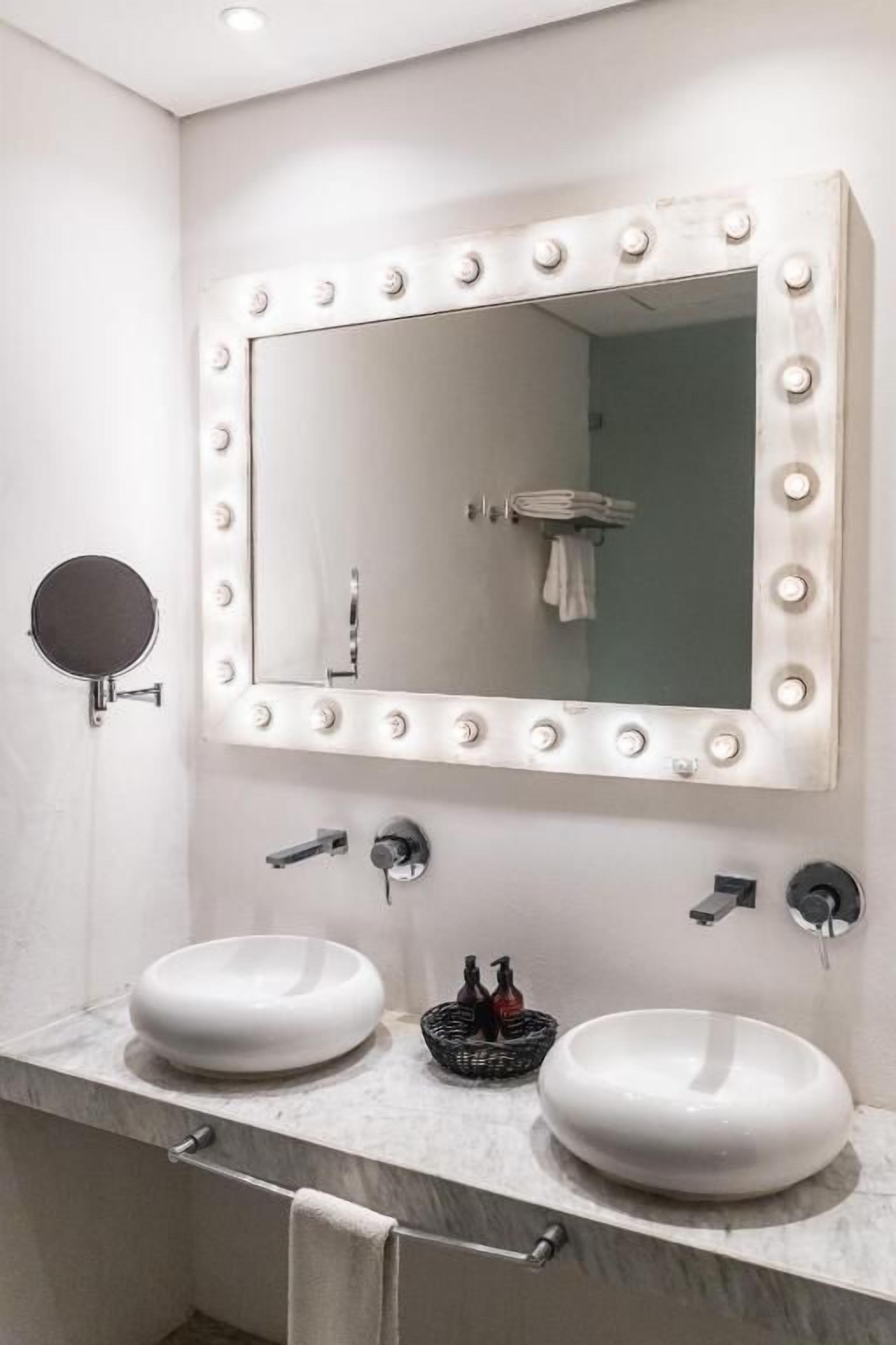 Une salle de bain avec deux lavabos, un grand miroir avec éclairage intégré et un porte-serviettes.