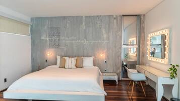 A modern bedroom with a large bed, bedside tables, a vanity with lights, and a mirror.