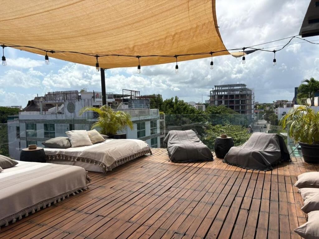 A rooftop terrace with wooden flooring, covered seating areas, and string lights.