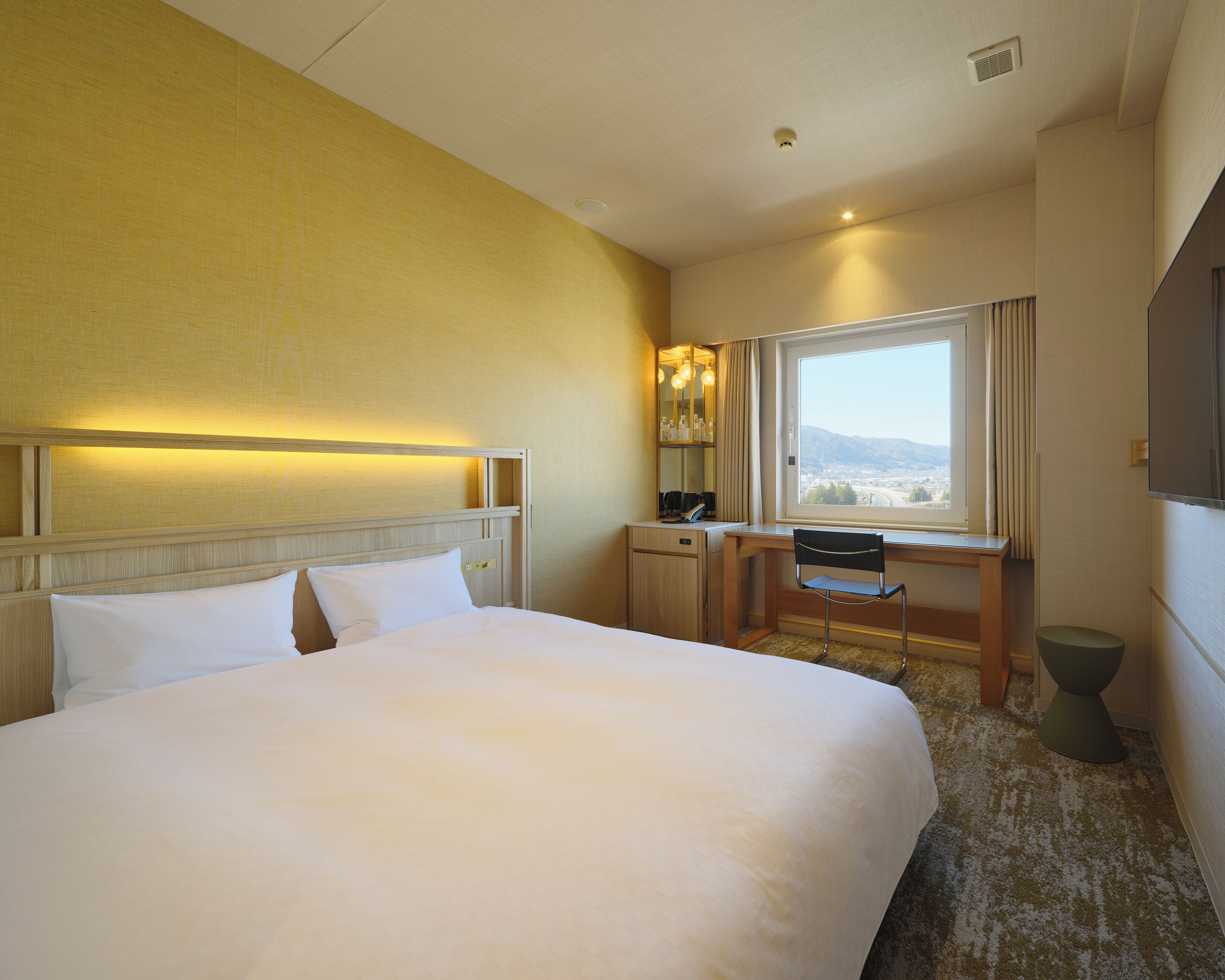 Habitación de hotel con una cama grande, un escritorio con silla, una ventana con vistas y un baño.