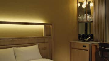 Una habitación de hotel con cama, escritorio, espejo y minibar.