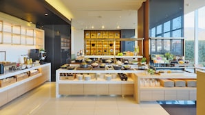 Cozinha de hotel moderna com disposição de buffet, exibindo diversas opções de alimentos e uma ampla janela com vista.