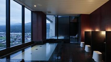 Ein moderner Wellnessraum mit großen Fenstern, Fußbodenheizung und Blick auf Stadt und Berge.