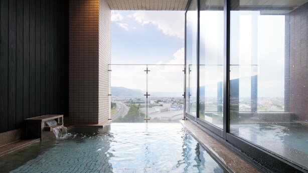 Piscina interior moderna com um banco e vista para o horizonte urbano através de amplas janelas.