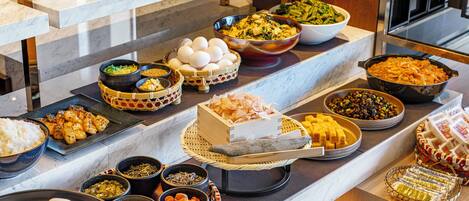 A buffet with various dishes and a cake on a marble counter.