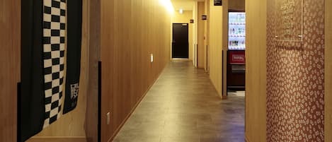 A hotel hallway with wooden walls, a checkered curtain, a vending machine, and a sign indicating a spa.