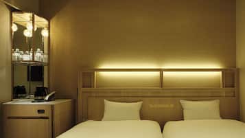 Une chambre d’hôtel comprenant un lit, des tables de chevet, un miroir et une tête de lit dotée d’un éclairage intégré.