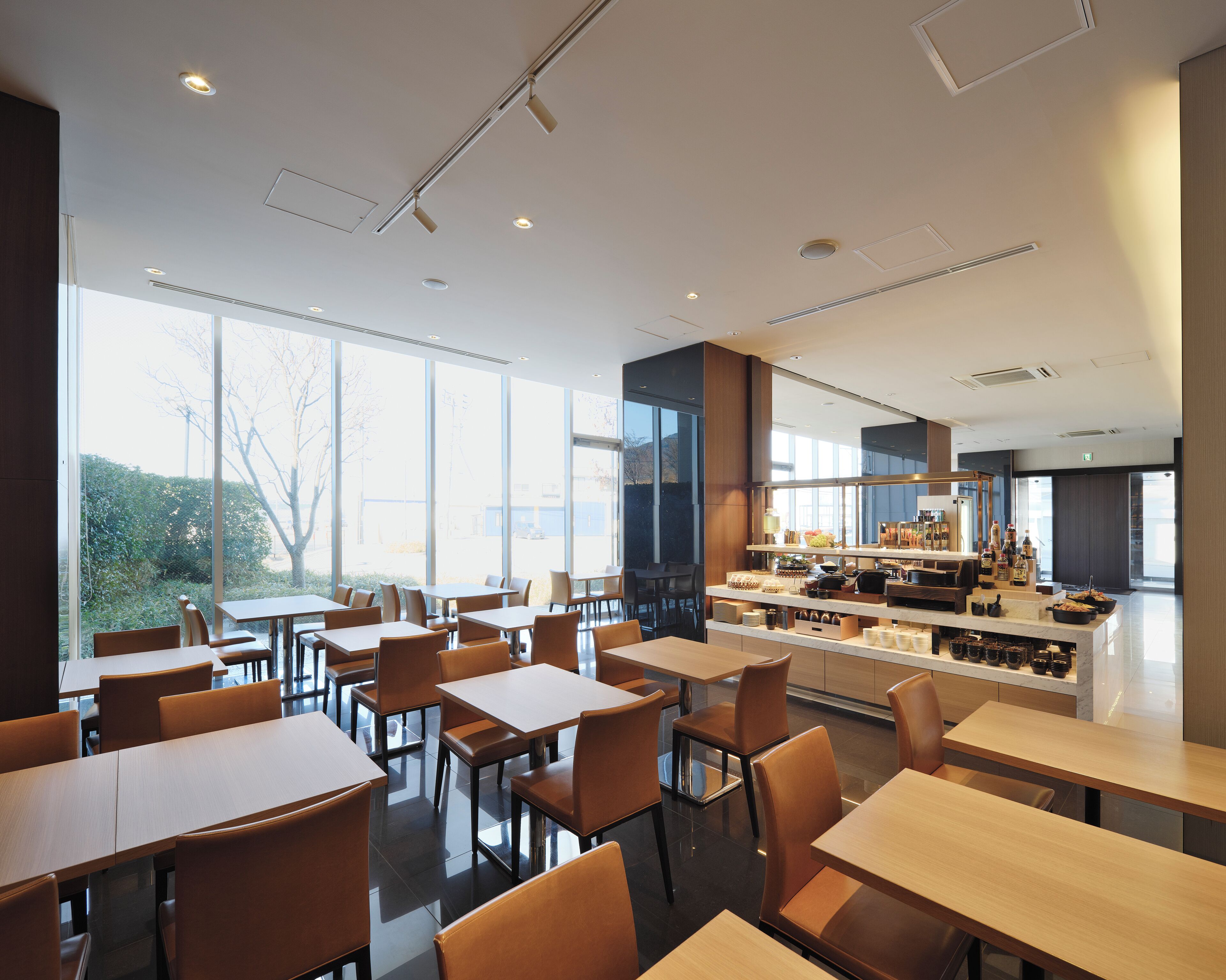A modern restaurant with a bar area, large windows, and a clean, contemporary interior.