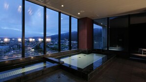 Uma área interna de piscina moderna com grandes janelas que oferecem vista para a cidade.