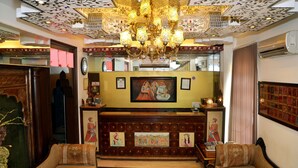 A traditional interior with a chandelier, wooden furniture, and decorative wall art. - Rajputana Haveli (Jaipur)