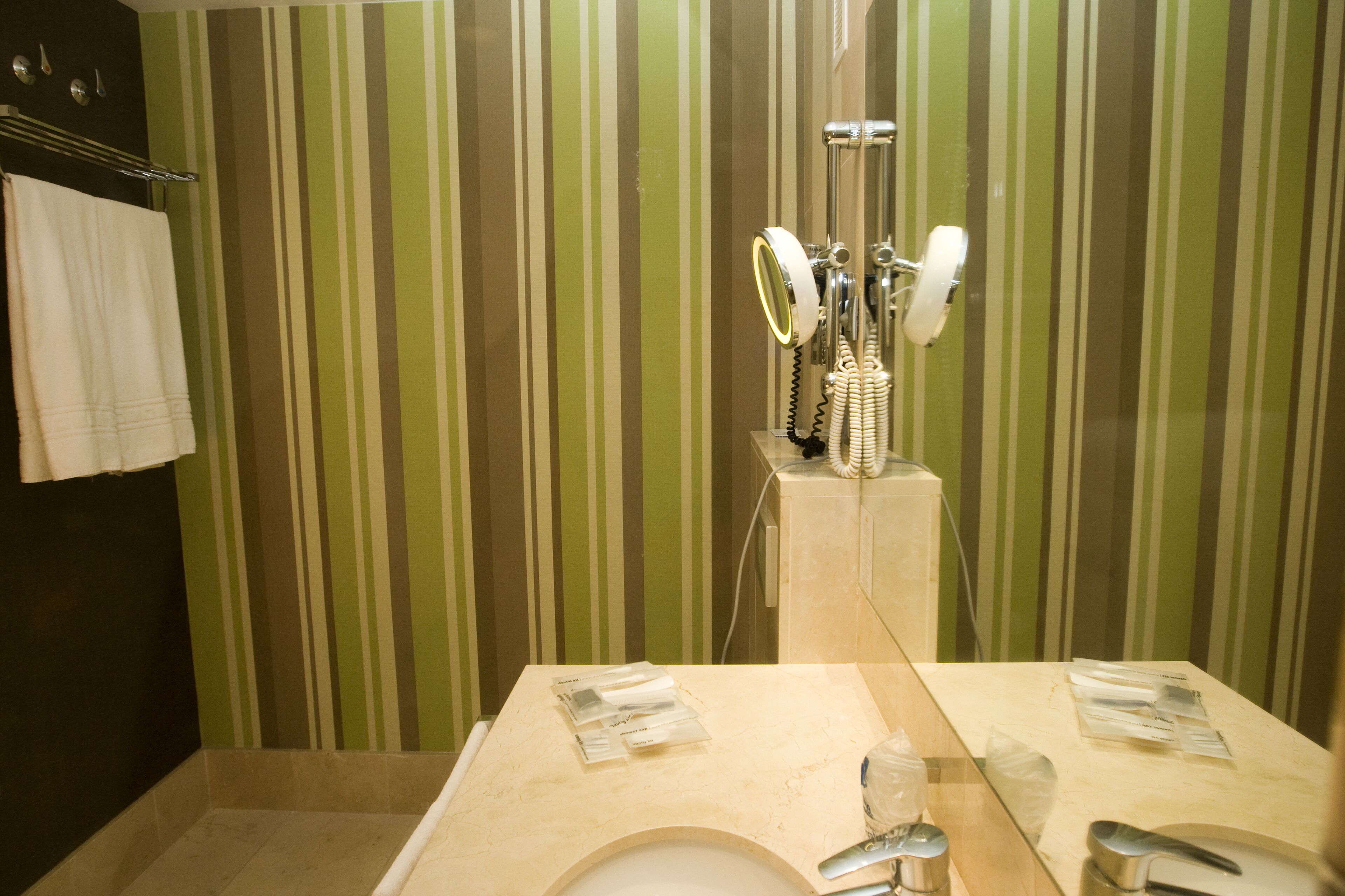 Un bagno con carta da parati a righe, un lavandino, uno specchio e un porta asciugamani.