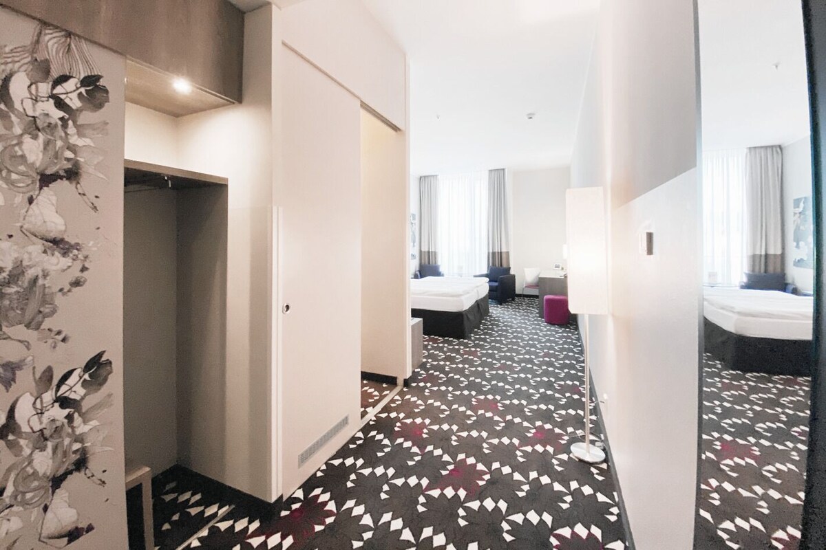 A hotel room with a bed, a desk, a chair, and a bathroom.