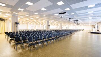 Une grande salle avec des rangées de chaises et une scène.