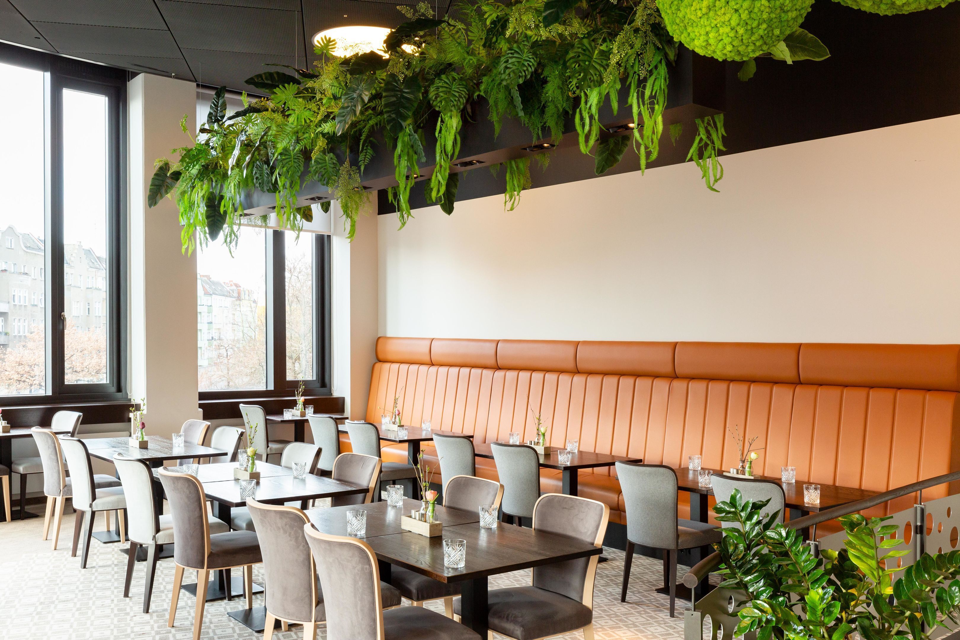 A modern dining area with tables and chairs, a large window, and a seating area with a cushioned bench.
