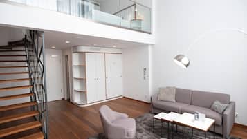 Una sala de estar moderna con una escalera, un sofá gris, una mesa de centro y un armario.