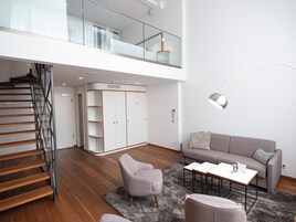 Una sala de estar moderna con una escalera, un sofá gris, una mesa de centro y un armario.