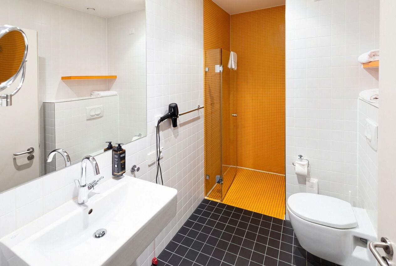 A modern bathroom with a white sink, mirror, and toilet.