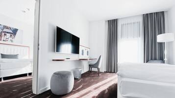 Ein modernes Hotelzimmer mit einem Bett, einem Schreibtisch, einem Fernseher und einem großen Fenster mit Vorhängen.